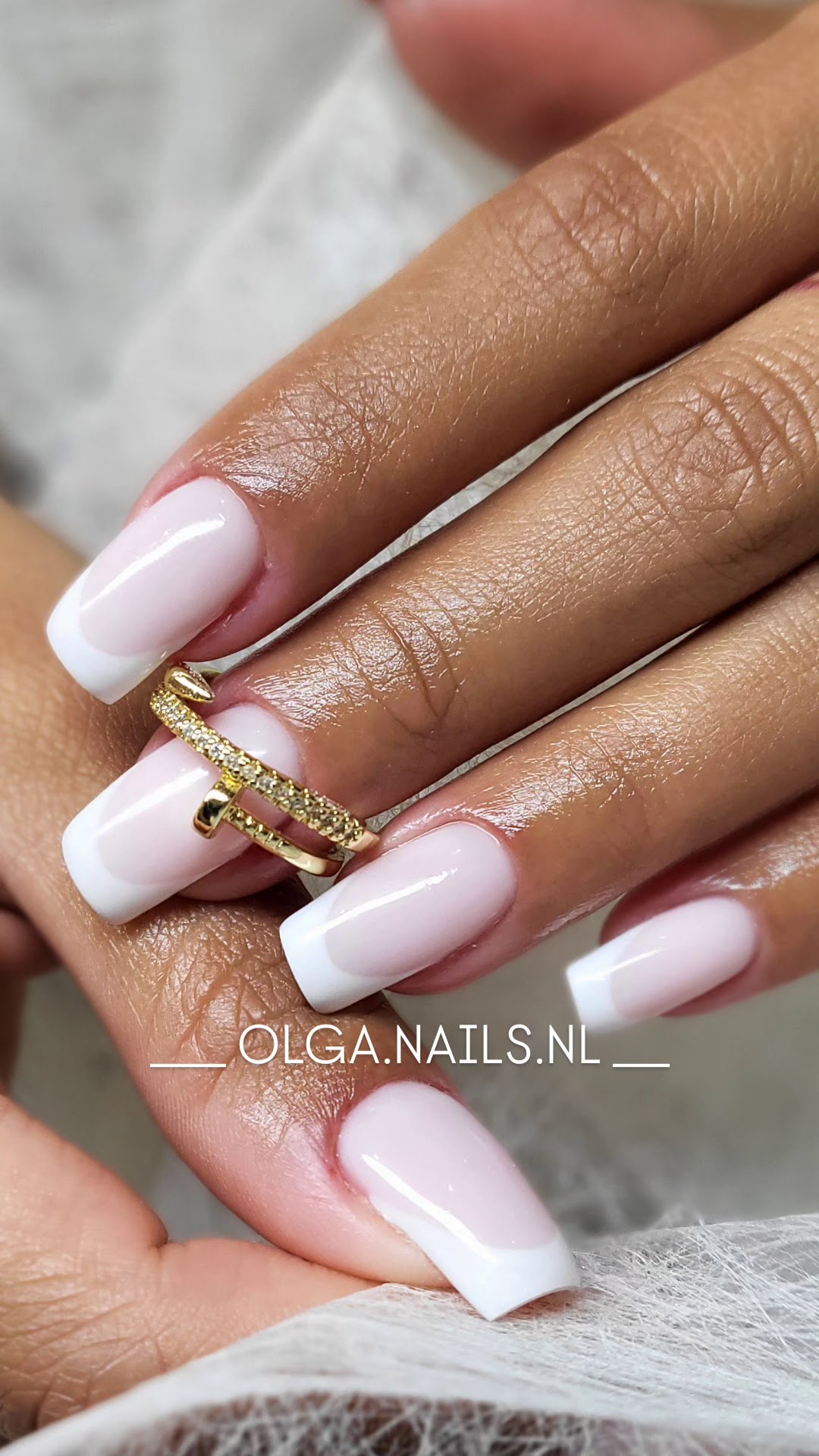 French manicure met witte tips en een gouden ring, op een witte vacht