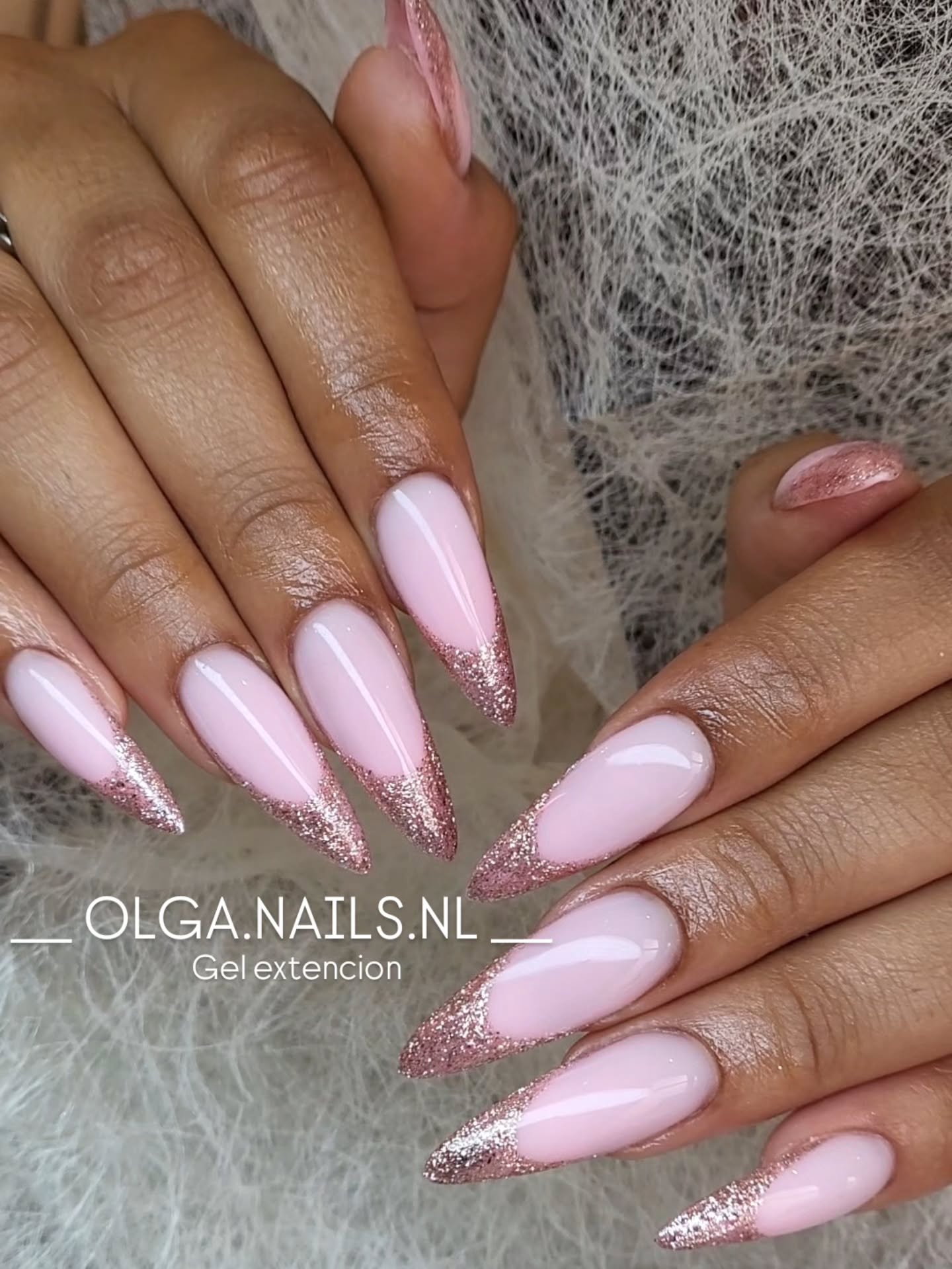 Lange amandelvormige gelnagels in roze met roze glitter ombre aan de punt